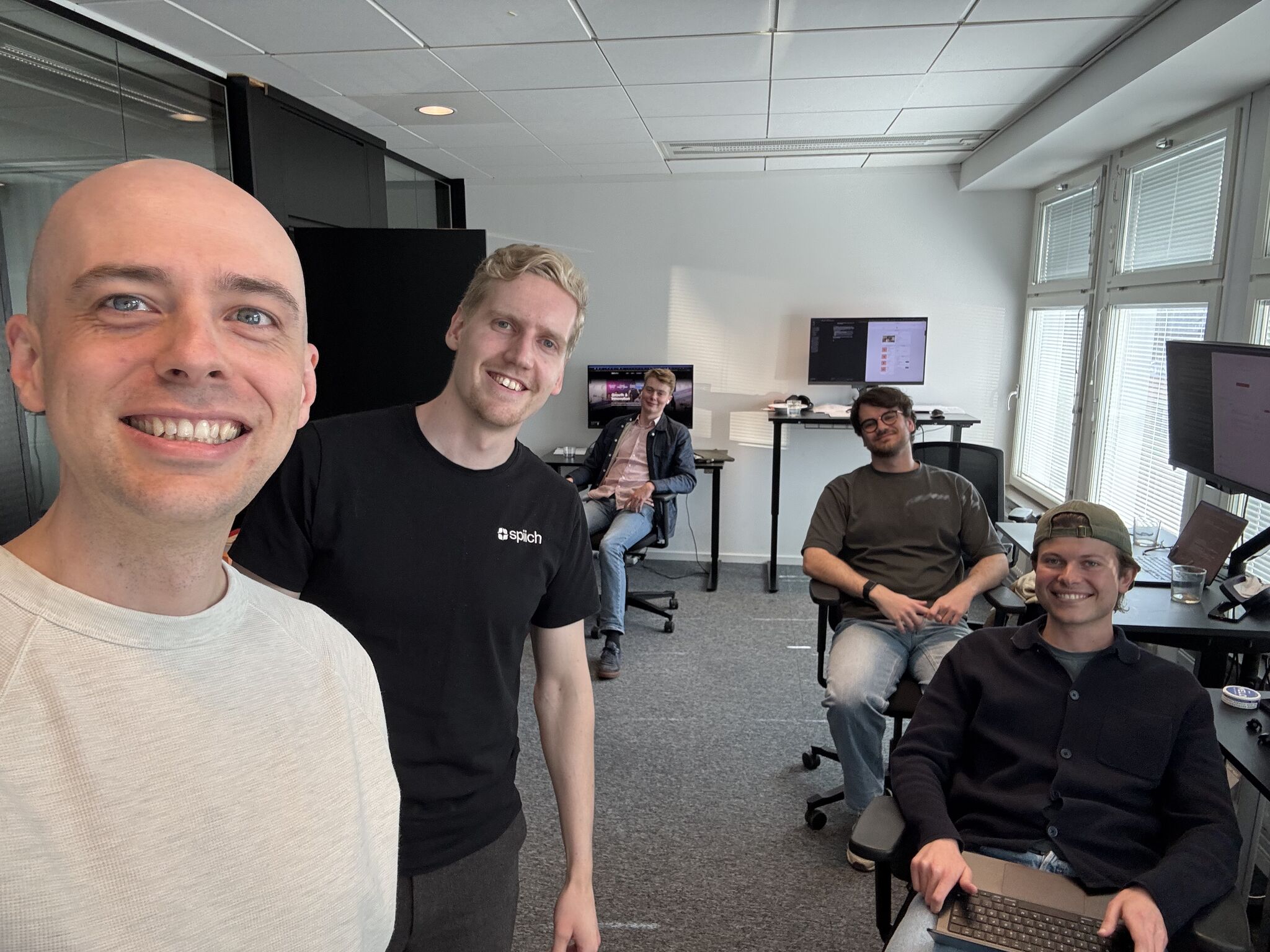 Five of the team gathered between the desks on a new joiner’s first day